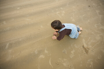 there is a young child playing in the sand on the beach