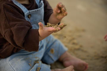 there is a small child sitting on the sand with his hands in the sand