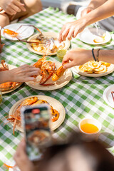 Happy man and woman travel the sea on summer beach holiday vacation. Asian man using smartphone taking picture food and drink during meeting party having lunch eating seafood with friends on the beach