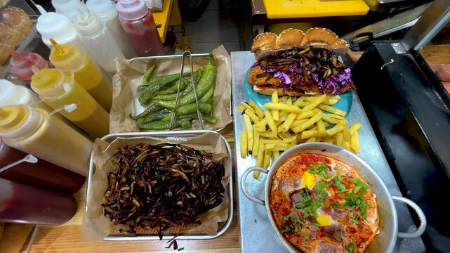 Shakshuka is a traditional Middle Eastern breakfast of eggs, peppers and tomatoes. Tel Aviv street food. French fries, peppers, a challah sabich sandwich with chicken schnitzel and eggplant.