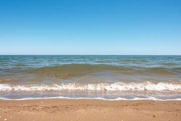 Tranquil wave at the shore on a serene beach with clear blue sky in a horizontal landscape for peaceful scene