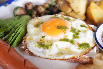 Breakfast plate with fried egg, avocado, and sausages served fresh