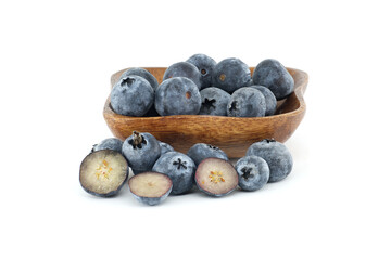 A wooden bowl overflowing with fresh blueberries, with some cut open to reveal the inside.