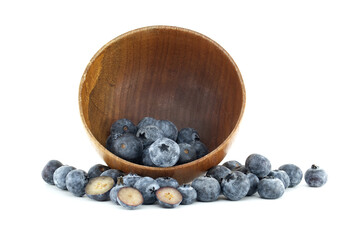 A wooden bowl spills fresh blueberries, some sliced in half, creating a healthy and inviting scene.