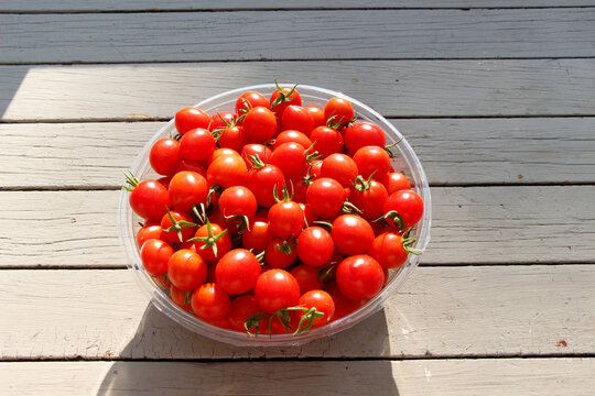 Ripe red cherry tomatoes in the bowl on wood table