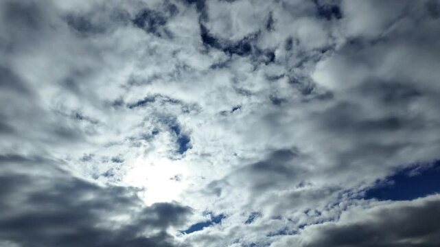 POV flying bellow a leyer of ethereal stratus clouds with a shining sun above in a blue sky. A pilot&rsquo;s perspective from a jet cockpit. 4K 60FPS