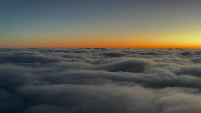 A pilot&rsquo;s perspective FPV POV from a jet arplane while flying at sunrise over a sea of grey color clouds with an orange color horizon. 4K 60FPS