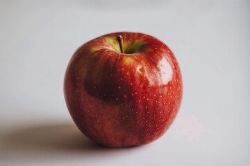 A fresh, red apple with a glossy surface, placed on a clean white background