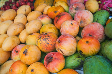 assortment of fresh tropical ripe mangoes on the counter at an Asian street market in Thailand