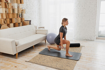 young athletic girl doing sports, stretching, yoga at home. Workout at home, in bedroom, living room