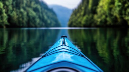 Fototapeta premium Blue kayak floating on a calm river surrounded by lush green forested mountains.