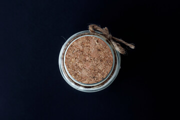 scented candle in glass candlestick covered with cork lid, top view, close-up on dark background