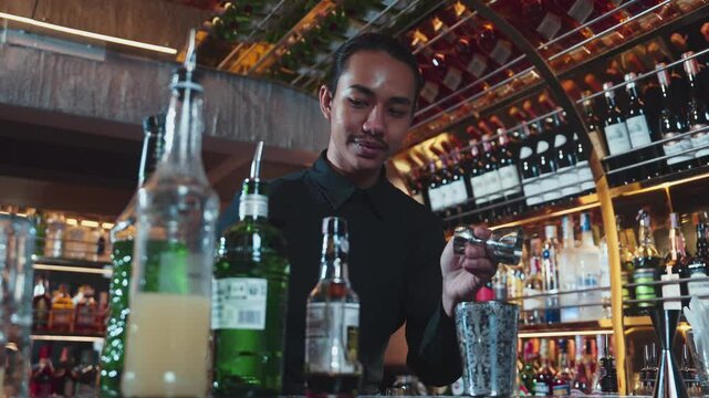 Asian bartender pouring mixed cocktail juice liqueur all ingredient into sliver shaker alcohol drink, making special advertisement creative tasty, focused refreshing showcase at bar luxury. Vinosity.