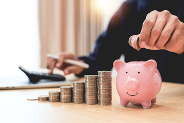 Businessman holding coins putting in pink piggy , Planning step up, saving money for future plan .