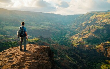 Obraz premium Professional stock photo of a Man with a Backpack Standing on a Cliff Overlooking a Valley