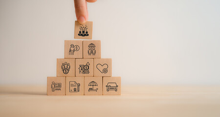 Employee benefits concept. A hand stacking wooden blocks with icons representing various employee...