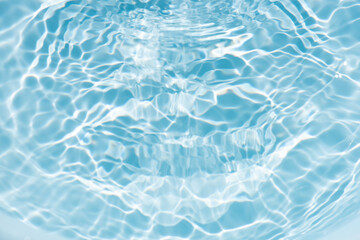 Blue water with ripples on the surface. Defocus blurred transparent blue colored clear calm water surface texture with splashes and bubbles. Water waves with shining pattern texture background.