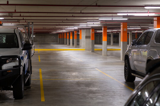 Two utes and a car parked in a mostly empty commercial car park.