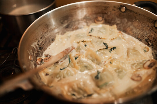 Tortellini pasta dish with creamy white sauce simmering in pan ready to serve