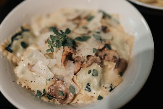 Tortellini pasta dish with creamy white sauce garnished with fresh oregano leaves