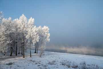 Winter morning landscape with river, water, forest and steam on the water.