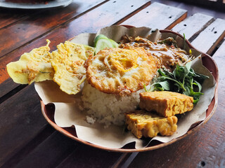 Nasi pecel or sego pecel is a typical Javanese Indonesian rice dish served with pecel sauce, vegetables, peyek, eggs, tempeh and other side dishes can be added.