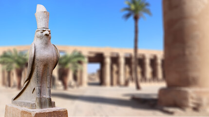 Horizontal banner with granite statue of falcon God Horus, palm and ancient columns, Karnak Temple...