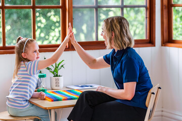 Girl and speech therapist high five in clinic in celebration