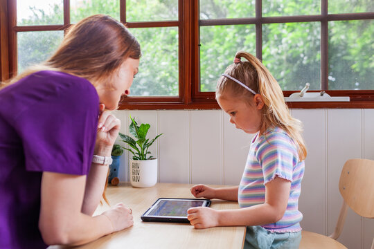 Speech therapist professional with child using technology to help with language development