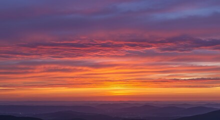 Fototapeta premium Vibrant sunset over rolling hills with dramatic clouds and distant valleys