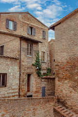 A narrow street in Urbino, a medieval town in Italy, where historic buildings with rustic stone facades tower on either side, creating a serene atmosphere.