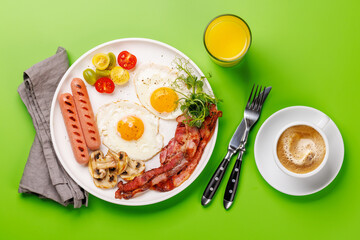 A classic breakfast plate featuring sunny-side-up eggs, crispy bacon, sausages, and fresh tomatoes