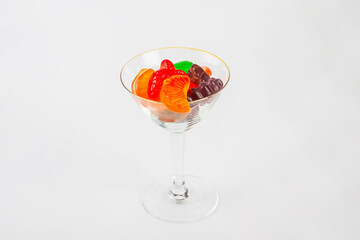 Fruit flavored worm shape, jelly candies in a glass on white background. 