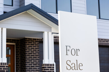 For sale sign outside of new brick house on real estate market