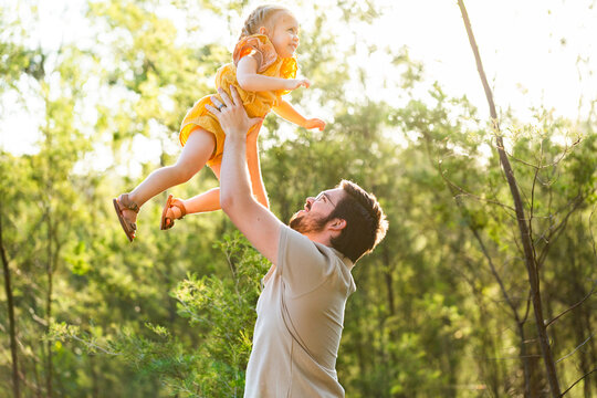 Dad playing with young daughter outside in green bushland
