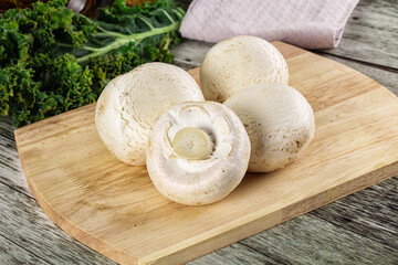White champignon mushrooms heap over board
