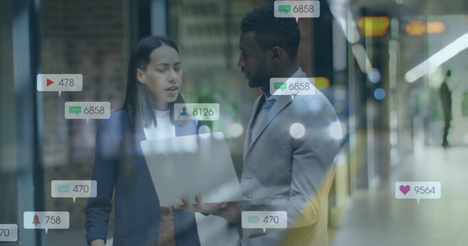 Image of social media notifications over diverse colleagues using laptop and talking