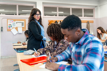 High school students taking exam with teacher supervising