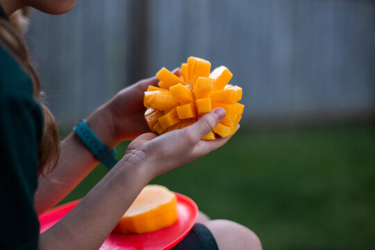 child eating a cheek of fresh sliced mango