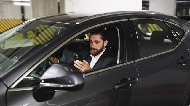 Smiling Caucasian businessman receives car keys from another person inside parking garage. Concept of car rental, business travel, mobility solution.