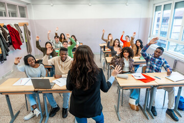 University students raising hands in classroom during lesson
