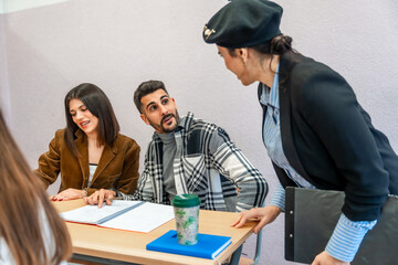 University professor helping students studying together at desk