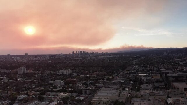 Aerial rising dolly shot of the Palisades Fire as seen from Hollywood during sunset in Los Angeles, California. 4K