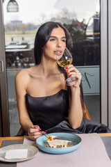 Beautiful woman in a restaurant eating dessert and drinking wine