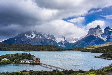 Fototapeta premium House on an island connected to the mainland by a bridge with mountains and rain clouds in the background in Patagonia