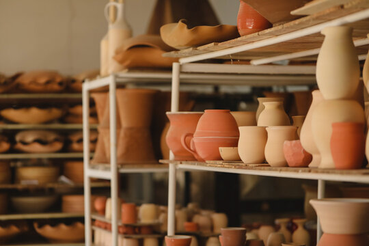 Diverse handcrafted pottery on rustic shelves in a workshop