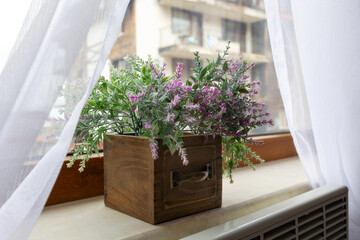 Artificial plant purple flower in flowerpot on window sill indoors, interior design
