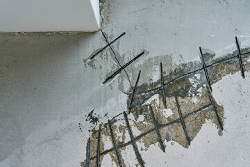 Close-up of concrete surface under repair with reinforcement bars inserted into cracks. Repairing...