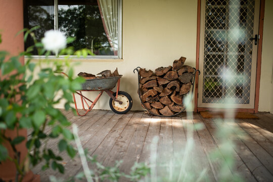 Wheelbarrow and stack of wood on verandah of country home ready for winter