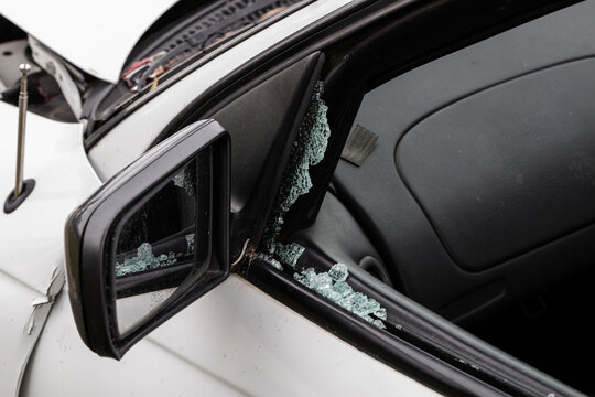 A broken car window and side mirror after a bad car crash accident in a white car